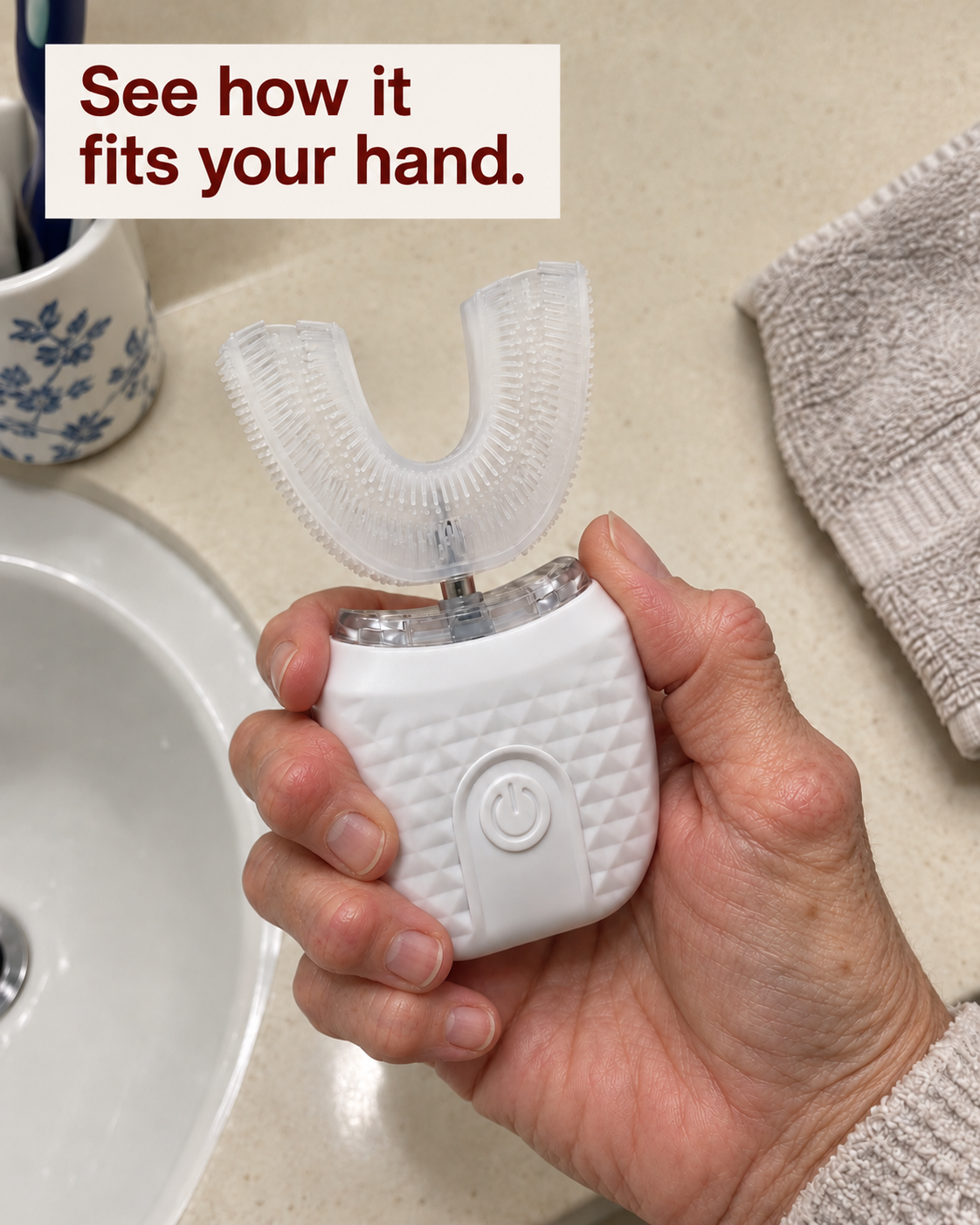 Dentarel U Brush held in a hand, showing the broad handle, central button and silicone mouthpiece.